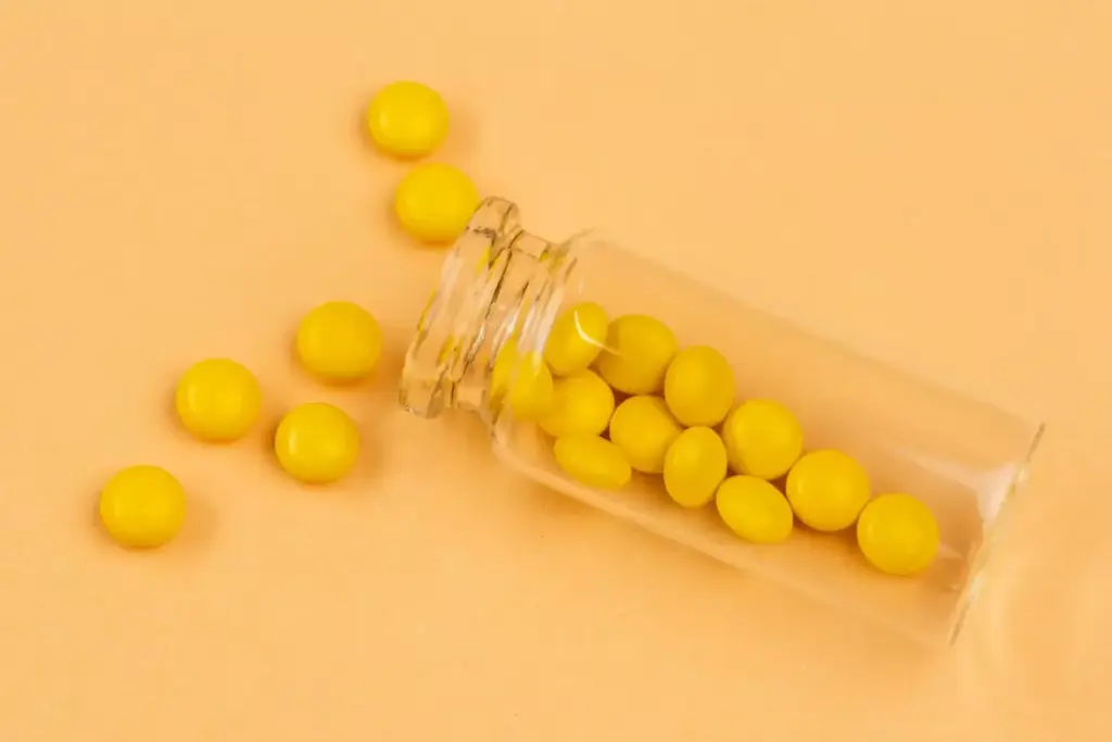 A glass beaker filled with amber-colored temozolomide capsules, resting on a stainless steel laboratory bench. The beaker is illuminated by warm, indirect lighting, casting soft shadows and highlights that emphasize the textures and forms of the capsules. In the background, blurred scientific glassware and equipment suggest a professional, clinical setting. The overall mood is one of medical innovation and promise, reflecting the crucial role of temozolomide in the treatment of glioblastoma, a deadly form of brain cancer.