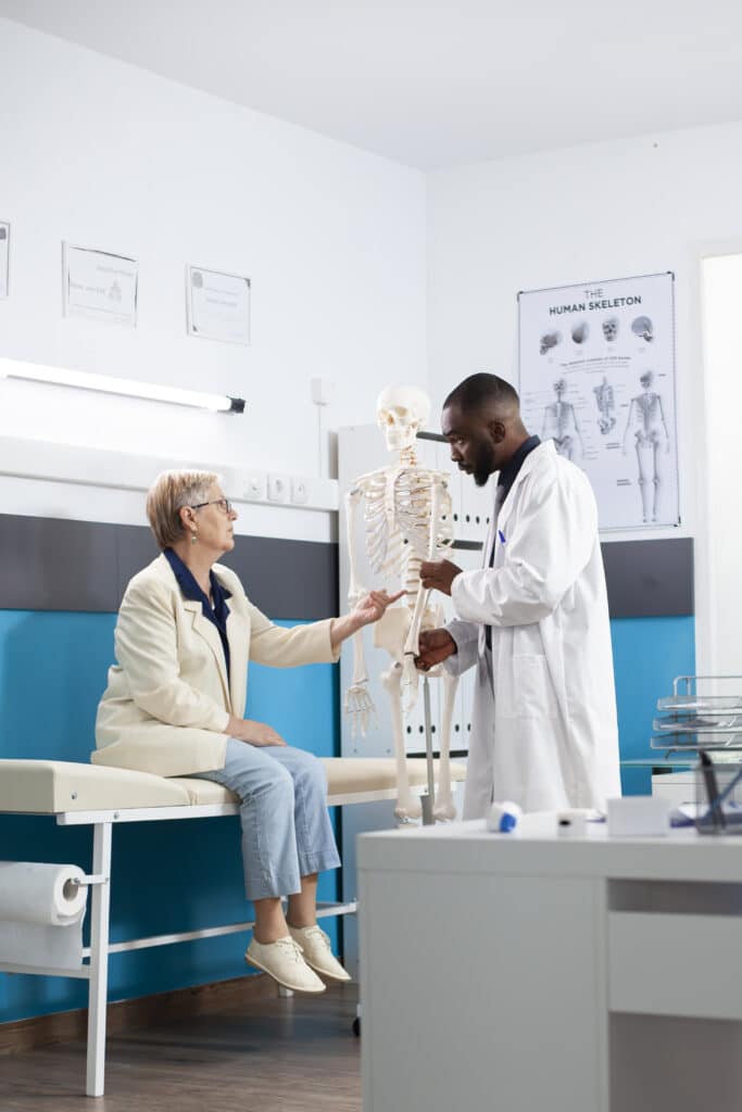 Doctor showing skeleton to retired woman
