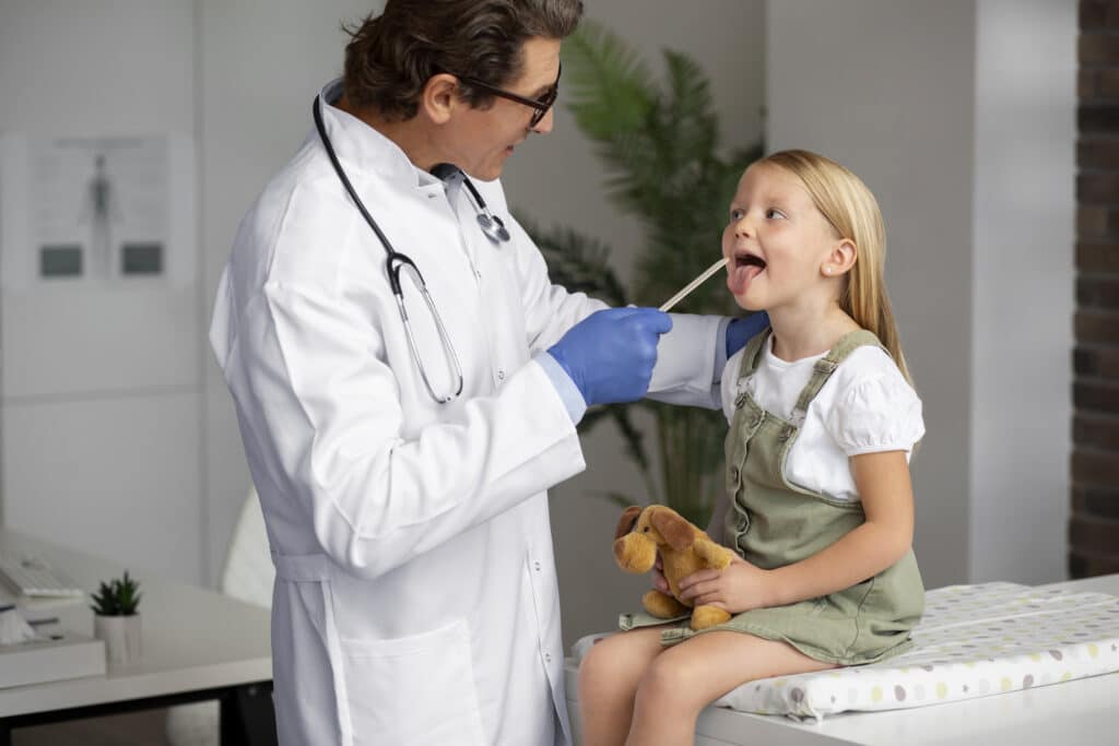 male doctor examining little girl holding teddy bear toy LIV Hospital